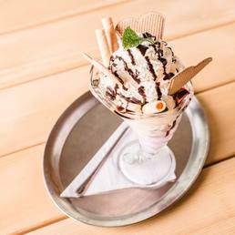 Eisbecher mit Schokosauce, Schlagobers und Waffelröllchen