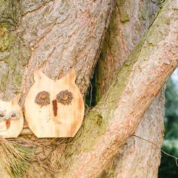 Geschnitzte Holzeule an einem Baumstamm im Gastgarten